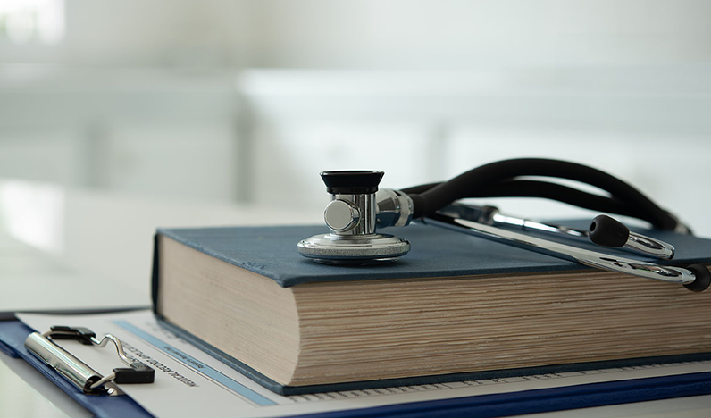 A stethoscope resting on a book and clipboard.